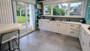 Eine moderne Küche mit großem Fenster, einer eingebauten Spüle und einem Essbereich mit Tisch und Stühlen.