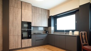Eine moderne Küche mit Holzausstattung, einem Einbauofen, einer Mikrowelle und einem Fenster mit Blick in den Raum.