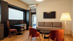 Ein modernes Wohnzimmer mit einer Couch, zwei Sesseln, einem Couchtisch und einem Fernseher.