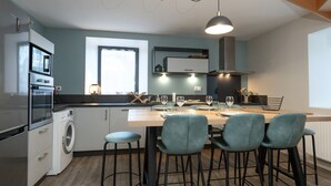 Une cuisine moderne avec un îlot central, des tabourets de bar et une fenêtre.