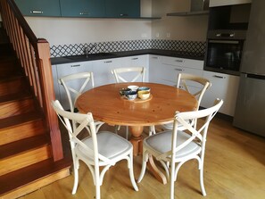 A kitchen with a wooden dining table, white chairs, and a black countertop.