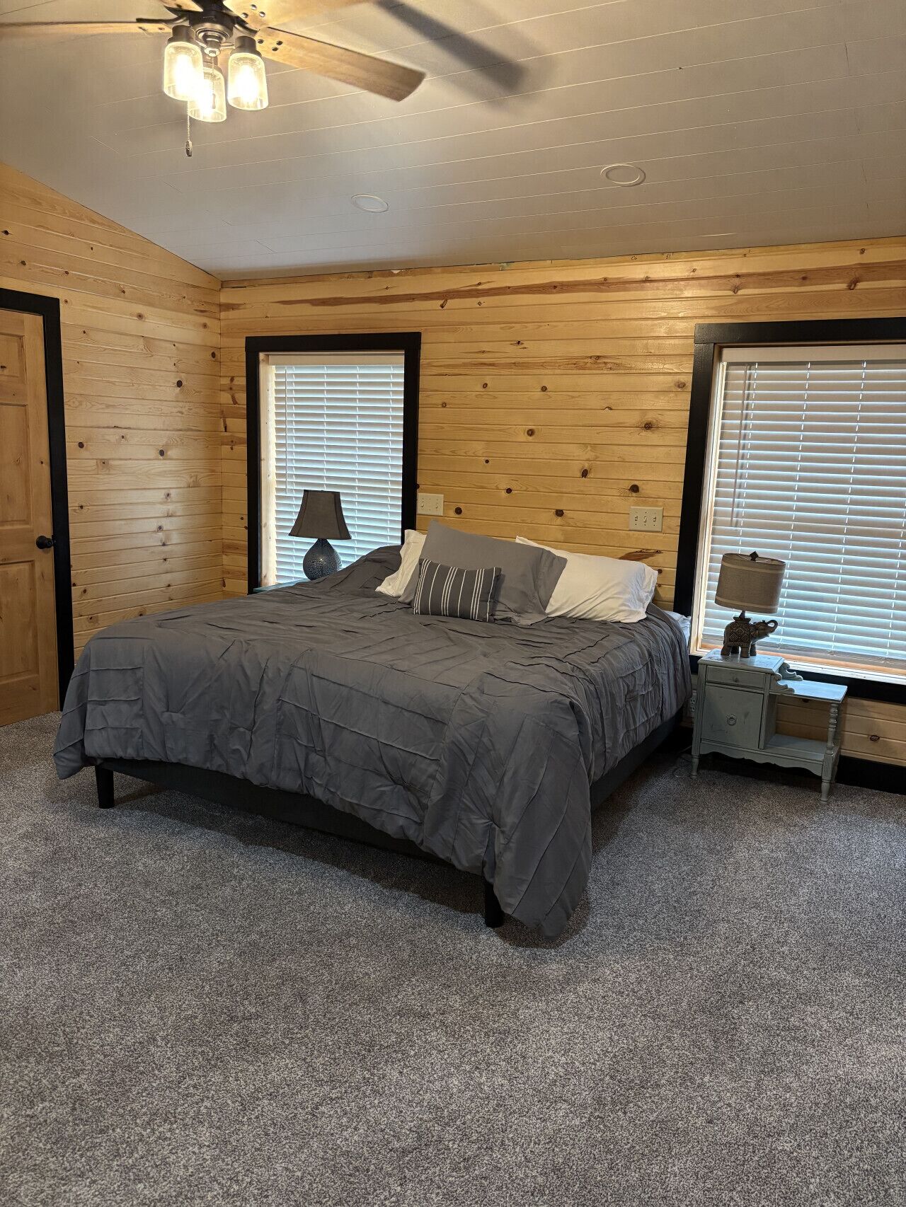 A bedroom with a bed, a nightstand, a lamp, and a ceiling fan.