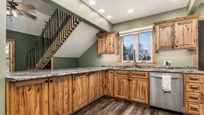 Una cucina moderna con mobili in legno, lavastoviglie in acciaio inossidabile e un piano di lavoro in marmo.