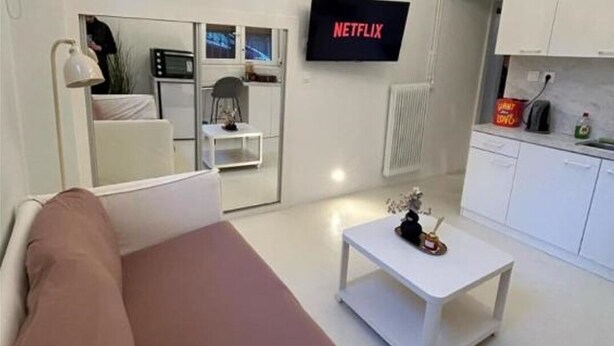 Ein modernes Wohnzimmer mit einer Couch, einem Couchtisch und einem an der Wand befestigten Fernseher.