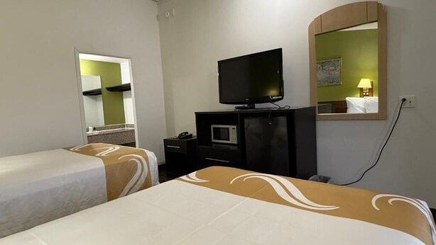 Habitación de hotel con dos camas, televisión, microondas y espejo.