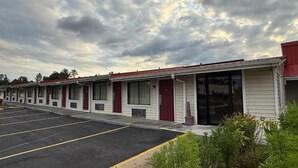Fila de edificios de motel con habitaciones individuales, un estacionamiento y un cielo nublado.