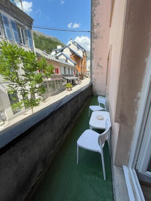 A balcony with a green artificial turf floor, white plastic chairs, and a view of buildings and a mountain. - Three-room apartment sleeps 6/7 in the center of Bareges (Barèges)