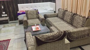 Uma sala de estar com um sofá branco, um sofá de vime e uma mesa de centro de vidro com um prato de comida.