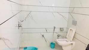 Casa de banho com sanita, lavatório e um balde azul.