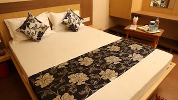 A hotel room with a bed, pillows, a bedside table with a water bottle, and a mirror.