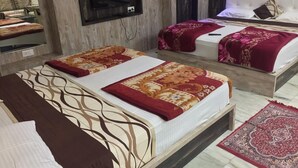 Quarto de hotel com duas camas, uma televisão presa à parede e um tapete estampado no chão.