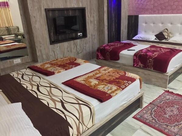 Une chambre d’hôtel avec deux lits, un téléviseur fixé au mur et un tapis à motifs sur le sol.