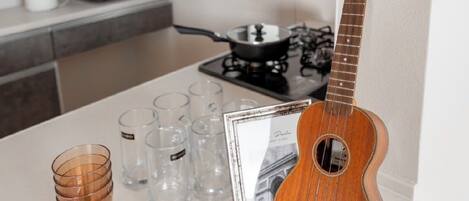 A kitchen with a guitar, glasses, and a framed picture on the counter.