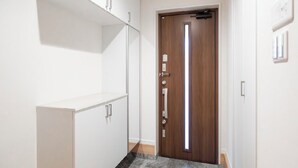 A hallway with a wooden door, white cabinets, and a marble floor. - Seiran Villa (Osaka)