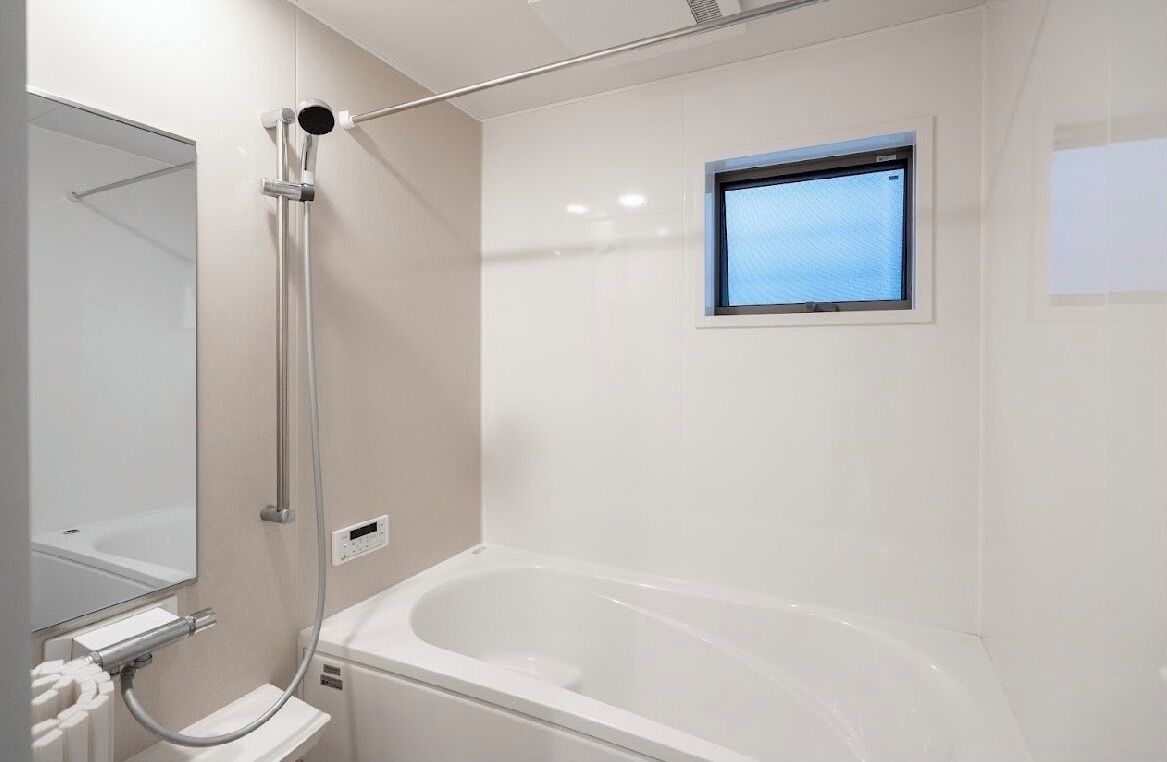 Ein modernes Badezimmer mit einer Badewanne, einer Duschbrause, einem Fenster und einem Spiegel.