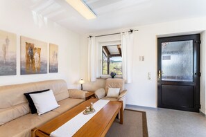 Ein Wohnzimmer mit einer Couch, einem Holztisch und einer Tür mit Milchglasscheibe.