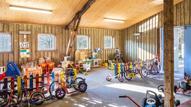 Ein Holzinnenraum mit Fahrrädern, Spielzeug und einem Spielbereich.