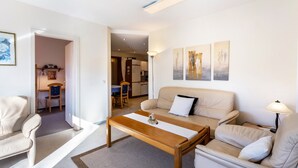 Ein Wohnzimmer mit einer Couch, einem Couchtisch, einer Lampe und Kunstwerken an der Wand.