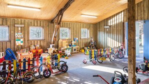 Un intérieur en bois agrémenté de vélos, de jouets et d’un espace de jeux.