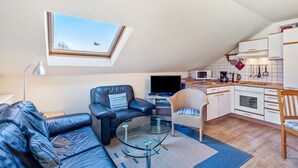 Un espace de vie compact comprenant une chambre en mezzanine, un coin repas et une kitchenette.