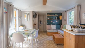 A cozy room with a dining table, chairs, a sofa, and a television. - Amorosa Mobile Home, Bonne Anse Plage at La Palmyre (La Palmyre)