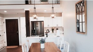 Una cocina moderna con armarios blancos, un refrigerador de acero inoxidable e iluminación colgante.