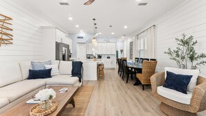 Ein modernes Interieur mit einer Couch, einem Esstisch, Korbstühlen und einem Deckenventilator.