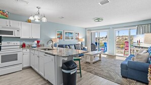 Een moderne keuken met witte kasten, een centraal eiland en een groot raam met uitzicht op de omgeving.