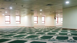 A large indoor space with a patterned carpet, white walls, and multiple windows. - Meezab Alkher Hotel (Makkah)