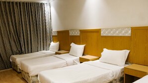 A hotel room with three beds, wooden headboards, and a wooden floor. - Meezab Alkher Hotel (Makkah)