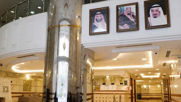 A lobby with a central column, a reception desk, and framed portraits on the wall. - Meezab Alkher Hotel (Makkah)