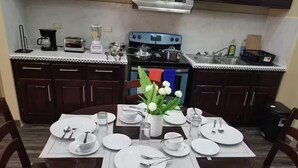 Un coin repas avec une table dressée pour quatre personnes, une cuisinière et un évier en arrière-plan.