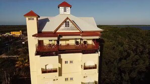 Un immeuble à plusieurs étages, doté d’une tour imposante, de balcons et offrant une vue sur une étendue d’eau.
