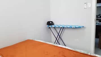 Una habitación con cama, tabla de planchar y armario.
