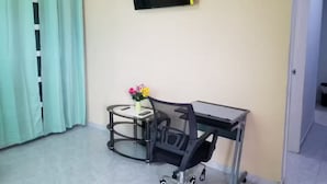 Een kleine kantoorruimte met een bureau, stoel en een televisie aan de muur.