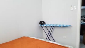 Une chambre avec un lit, une planche à repasser et une armoire.