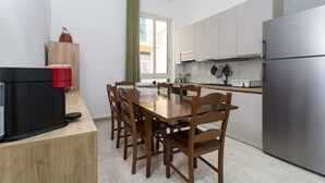 A modern kitchen with a dining table, chairs, a refrigerator, and a coffee machine. - VomeroMetroNest By Dimorra  (Napoli)