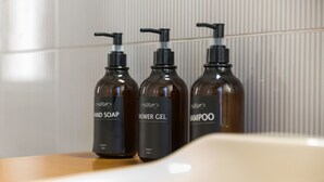 Three bottles of hand soap, shower gel, and shampoo on a wooden surface. - VomeroMetroNest By Dimorra  (Napoli)
