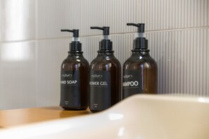 Three bottles of hand soap, shower gel, and shampoo on a wooden surface. - VomeroMetroNest By Dimorra  (Napoli)