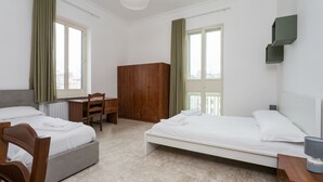A hotel room with two beds, a wooden wardrobe, a desk, and a chair. - VomeroMetroNest By Dimorra  (Napoli)