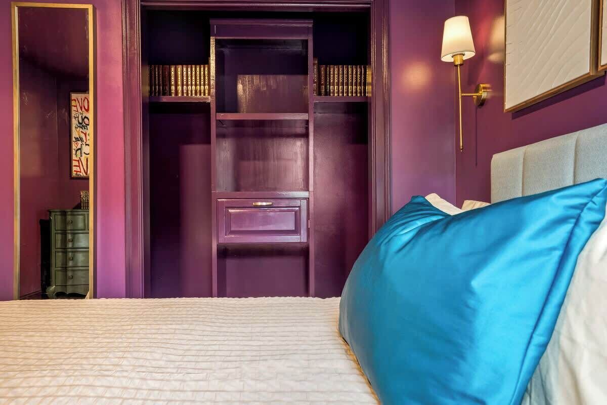 Ein Schlafzimmer mit einem Bett, einem lila Kleiderschrank und einem Nachttisch mit Lampe.
