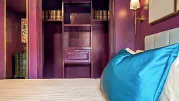 Ein Schlafzimmer mit einem Bett, einem lila Kleiderschrank und einem Nachttisch mit Lampe.