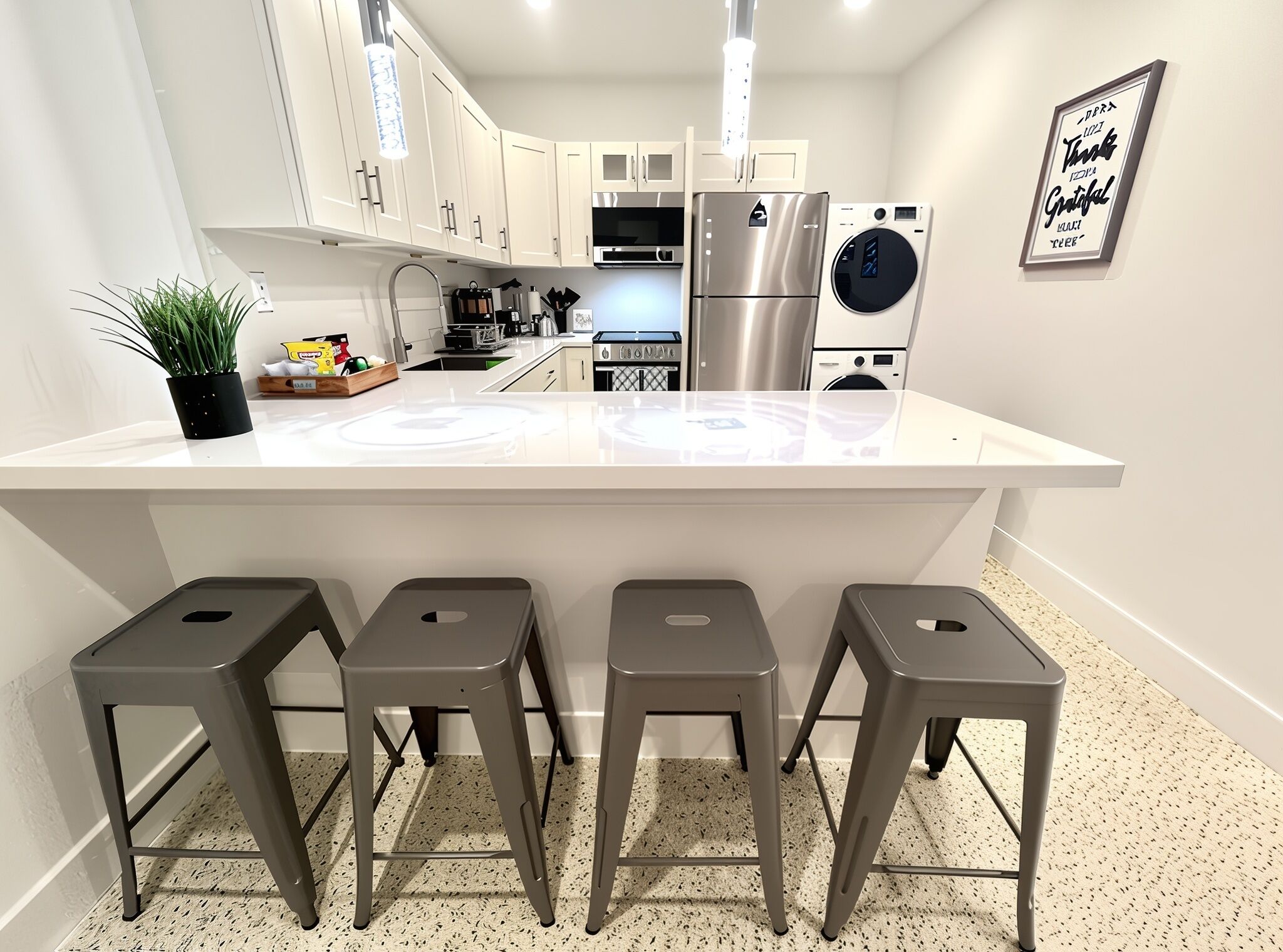 A modern kitchen with a central island, stainless steel appliances, and bar stools.