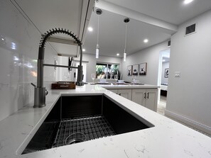 A modern kitchen with a built-in oven, stainless steel appliances, and a large island with a sink. - Casitas at Coconut Grove (Miami)