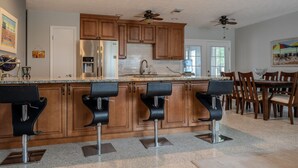 Una cocina moderna con armarios de madera, electrodomésticos de acero inoxidable y una barra con taburetes.