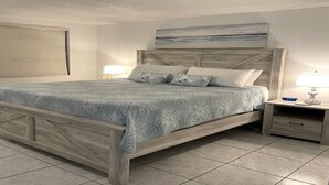 Una camera da letto con un letto in legno, un comodino con una lampada e un'opera d'arte appesa al muro.