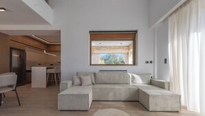 Una sala moderna con un sofá seccional, una mesa de centro redonda de madera y vistas a través de una ventana.