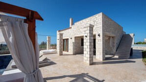 Un edificio de piedra con piscina, mobiliario exterior y una pérgola de madera.
