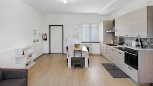 A modern kitchen with a dining area, wooden flooring, and a built-in stove. - Casa Vacanza Annì with Wi-Fi and Air Conditioning (Vico Equense)