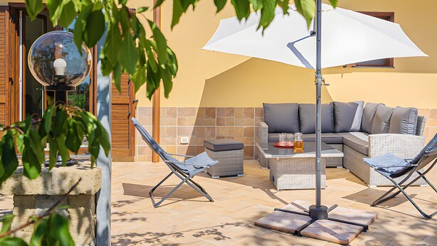 An outdoor seating area with a sofa, two lounge chairs, a table with a drink, and a large umbrella. - Casa Vacanza Annì with Wi-Fi and Air Conditioning (Vico Equense)
